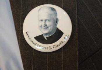 A member of the faith wears a pin in memory of Father Ciszek.