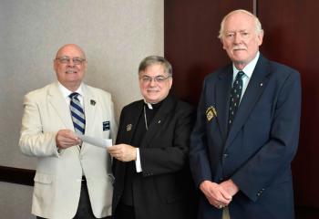 Jim Szoszorek, left, and John Philapavage present Bishop Schlert with a $1,580 check from the Knights of Columbus Label Program for promoting vocations in the Diocese.
