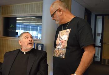 Monsignor John Campbell, left, pastor emeritus of Queenship of Mary, enjoys a conversation with Hector Lopez.