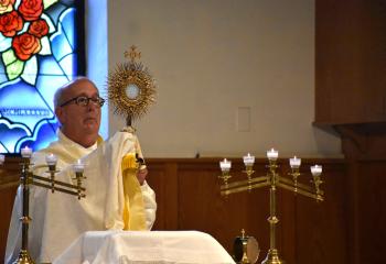 Deacon Donald Elliott lifts the Holy Eucharist before placing the sacrament on the altar for adoration. (Photo by John Simitz)