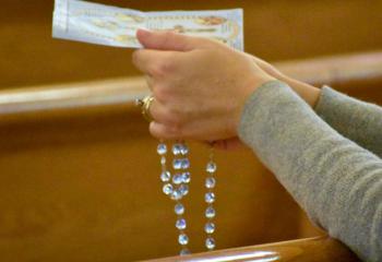 A member of the faith prays the rosary at Sacred Heart. (Photo by John Simitz)