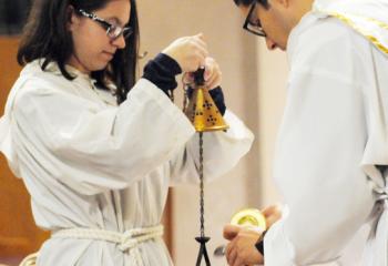 Altar server Haley Zambito, left, holds the censer as Deacon Esposito prepares the incense to purify the altar. (Photo by Ed Koskey)