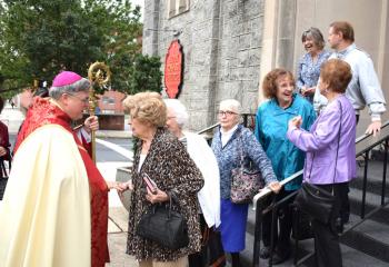 Bishop Schlert, left, greets faithful exiting Holy Rosary after celebrating Mass and discussing the power of the rosary.
