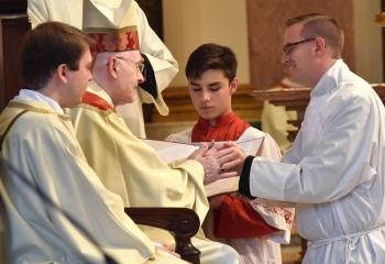 Deacon John Hutta promises obedience to the ordinary (bishop of diocese). At left are Deacon John Rother and Bishop Edward Cullen. (Photo by John Simitz)