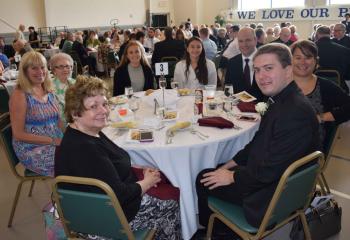 Father John Rother celebrates with his family at the Ordinandi Dinner honoring Father Rother as the Diocese of Allentown’s newly ordained priest June 19 at St. Mary, Hamburg. Seated are, clockwise from front, grandmother Judith Liaw, aunt Marianne Bright, grandmother Joan Rother, sister Gracia Rother, sister Melinda Rother, dad John Rother and mother MarySue Rother. The Serra Clubs of the Diocese of Allentown District I-80 hosted the evening. (Photo by John Simitz)