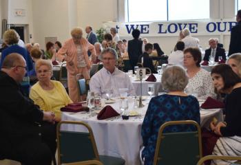 Father Eric Arnout, administrator of Assumption BVM, Slatington, left, enjoys the evening with other guests. (Photo by John Simitz)