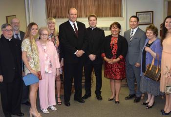 Msgr. Alfred Schlert, left, diocesan administrator, greets Father Rother and his family before the ceremony, from left: his uncle Michael Rother, his sister Gracia Rother, his grandmother Joan Rother, his aunt Marianne Bright, his father John Rother, his mother MarySue Rother, his uncle William Liaw, his grandmother Judith Liaw, and his sister Melinda Rother. (Photo by John Simitz)