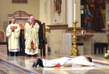 Deacon Peter Schutzler, left and Bishop Cullen chant the litany as Father Rother prostrates himself before the altar during the Litany of Supplication. (Photo by John Simitz)