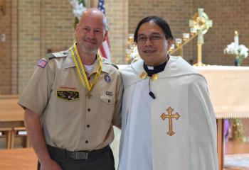 Father Eric Tolentino presents Todd McGreggor with the St. George Award. (Photo by John Simitz)