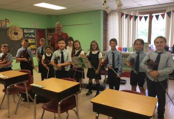 Third-graders gather with music instructor Simon Maurer during violin lessons May 31, from left, Derek Hertz, Aidan Becker, Jacob Philyaw, Madeline Michael, Paul Zuk, Nicole Knoblauch, Lily Snyder, Olivia Lesher, Colten Brown, Dalton Seisler and Saxton Donton. (Photo courtesy of St. Ambrose School)