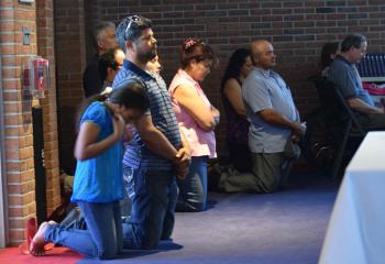 Those attending the standing-room only opening Mass kneel at the consecration. (Photo by John Simitz)