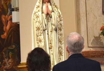 A couple admires the statue of Our Lady of Fatima. 