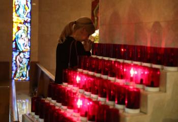 A woman prays during an interfaith memorial service Oct. 2 in Las Vegas for victims of a shooting spree directed at an outdoor country music festival late Oct. 1. A gunman perched in a room on the 32nd floor of a casino hotel unleashed a shower of bullets on the festival below, killing at least 59 people and wounding another 527. (CNS photo/Lucy Nicholson, Reuters)