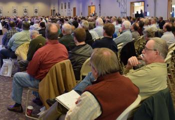 An estimated 600 men listen to a speaker at the conference.