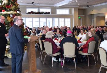 Msgr. David James, left, listens as Paul Acampora welcomes guests.