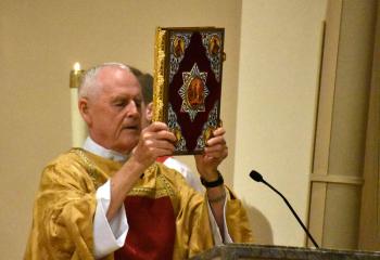 Deacon William Hassler carries the Book of Gospels.