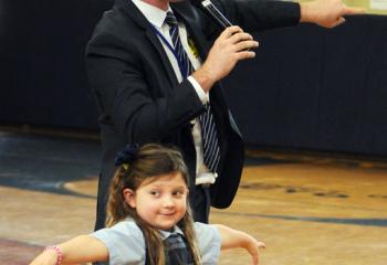 Makayla Hoole, first grade student at Holy Family School, Nazareth, volunteers to assist Dan Skeldon during his weather presentation for the school. (Photo by Ed Koskey)