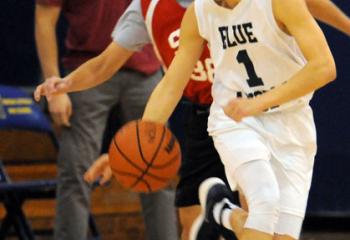 St. Joseph the Worker’s Sam Morgan (1) drives past St. Thomas More’s Patrick Adams (38) during the Feb. 25 high school boys’ championship game.