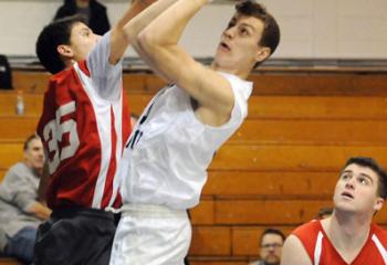 Tyler Hayes (0) of St. Joseph the Worker looks to makes a layup as St. Thomas More’s James Haag (35) blocks and St. Thomas More’s Zack Higgins (44) watches during the high school game.