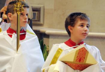 Altar server Ethan Willard, left, holds the bishop’s staff and altar server John Zawistowski holds the bishop’s miter during the special Mass. 