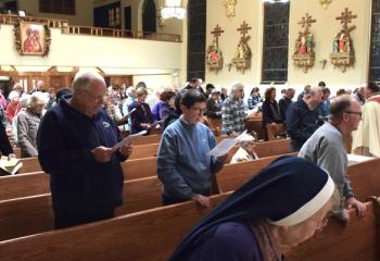 The congregation sings during the Mass as Father Martin Kern performs the sprinkling rite.