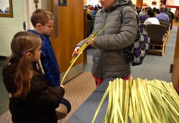 Heather Spencer, right, shows her children Cole, center, and Lilah a palm leaf before Palm Sunday Mass March 25 at St. Francis de Sales, Robesonia. 