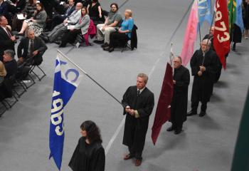 Alumni process into Billera Hall carrying flags representing the year they graduated from DeSales.