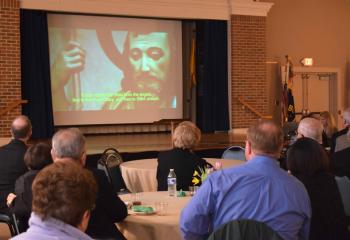 Guests view the BAA video. The appeal’s goal is to raise $5 million to help those in need.