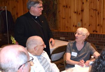 Bishop Alfred Schlert, left, converses with George and Jean Bruker, parishioners of Immaculate Conception, Jim Thorpe.