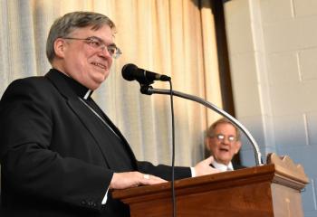 Bishop Alfred Schlert addresses those gathered as Joseph Bechtel listens at right. (Photo by John Simitz)