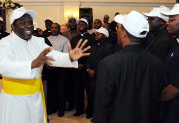 Apostles of Jesus Father Deogratias Rwegasira, then pastor of Our Lady of Mercy, Easton, leads a group of fellow AJ priests singing songs during the dinner after the 40th anniversary Mass July 24, 2008. (File photo)