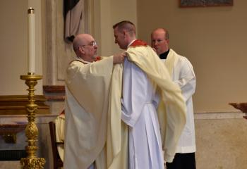 Monsignor Joseph DeSantis, left, vests Father Hutta during Investiture with Stole and Chasuble.
