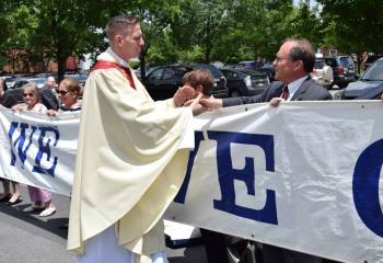 Father Hutta greets Serrans holding the sign “We Love Our Priests” outside the cathedral.