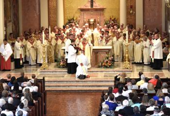 Bishop Schlert, priests of the Diocese of Allentown and visiting clergy pray over the newly ordained Father Hutta.
