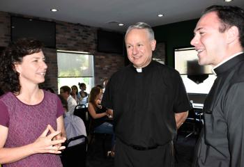 Kelly Anderson, left, chats with Deacon John Maria and seminarian Philip Mass during a break in the evening session.