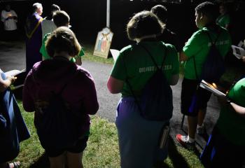 Holding candles, everyone prays during the July 18 Stations of the Cross. Philip Maas and Deacon John Maria stand at left.