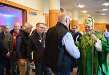 Bishop Schlert introduces himself to men attending the conference after Mass.