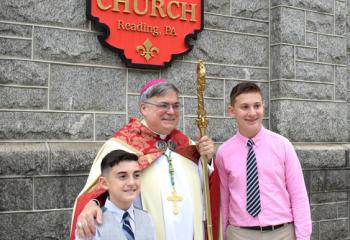 Bishop Schlert, center, stands with Emilio DeCarlo, left, and Rocco DeCarlo outside Holy Rosary, which was dedicated Oct. 2, 1904.