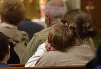 Aurelia Moser, left, naps on the shoulder of her mother, Joey Moser while listening to music by Wagner during the concert. The evening centered on Holy Hour and featured opportunities for confession, prayer for others, mediation on vocations and recitation of the rosary.