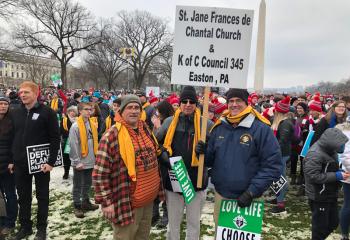Mike Hunsicker, grand knight of Knights of Columbus Union Council 345 that sponsored the bus for St. Jane, right holding the sign, joins fellow knights of the council at the march. (Photo courtesy of Andrew Azan)