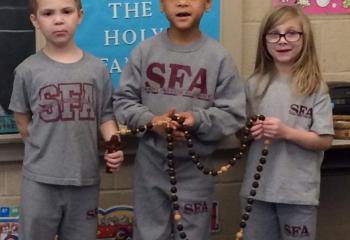 First-graders of St. Francis Academy Regional School, Bally, from left, Jakub Furniss, Micah Acholla and Lahela Kiefer lead their classmates in praying a decade of the rosary Jan. 18 in support of the national March for Life. (Photo courtesy of St. Francis Academy Regional School