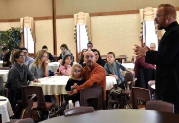 Father Mark Searles, director of the Diocesan Office for Vocations Promotion and chaplain of Allentown Central Catholic High School, right, welcomes the families in the parish center. 