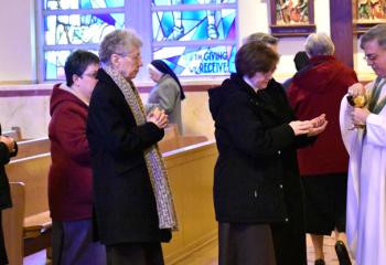 Bishop Schlert distributes Communion to sisters.