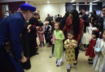 Father John Hutta, left, offers Vietnamese “lucky money” to children.