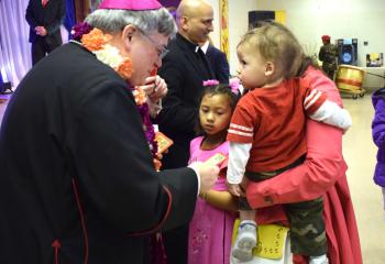 Bishop Schlert, left, distributes “lucky money” in honor of the Vietnamese tradition of adults and children exchanging the offering for health and longevity.