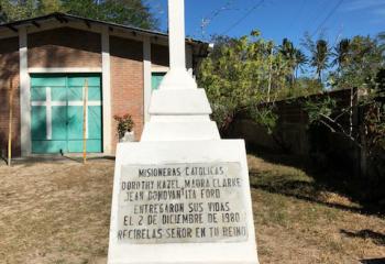 A white cross memorializes four American church women who were brutally murdered and buried on the side of the road.  