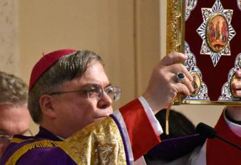 Bishop of Allentown Alfred Schlert raises the Book of Gospel to bless catechumens, sponsors and the faithful.