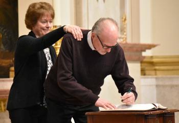 Jeff Gerstenblith, enrolls his name in the Book of Elect with the support of his sponsor, Joan McGorvey, parishioner of Our Lady of Mercy, Easton.