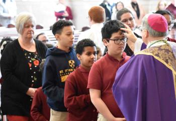 Fourth-graders in line to receive ashes are, from left, Paul Tran, Angel Herdandez and Yariel Gonzalez, along with Cathedral parishioners.(Photo by John Simitz)
