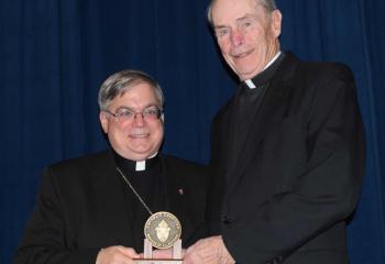 Bishop Schlert, left, presents the medallion to Monsignor Smith.